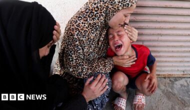 A woman comforts a child at al-Aqsa Hospital in Deir al-Balah, after medics said at least 15 people were killed in an Israeli strike at a roundabout, in central Gaza (10 July 2025)