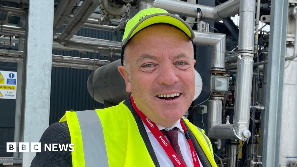 Aviation Minister Mike Kane stood in front of a network of pipes and machinery at the University of Sheffield's Advanced Manufacturing and Research Facility, wearing a high-visibility jacket and cap.