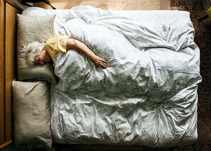 Elderly woman lying in bed alone, illustrating patients delaying help with shocking consequences and serious health risks.