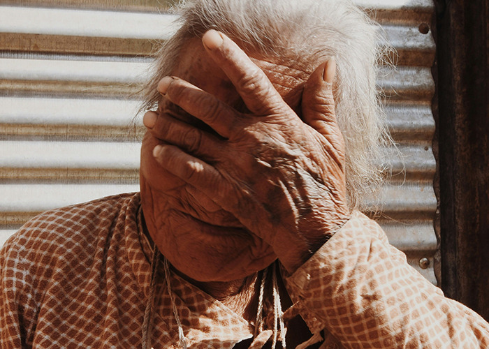 Elderly person covering face, symbolizing patients who delayed help with shocking health consequences.