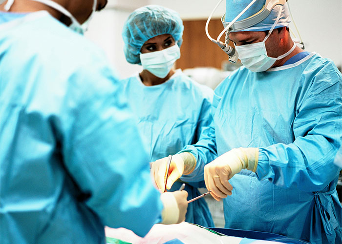Surgeons in blue scrubs performing a medical procedure highlighting risks of patients delaying help with shocking consequences.