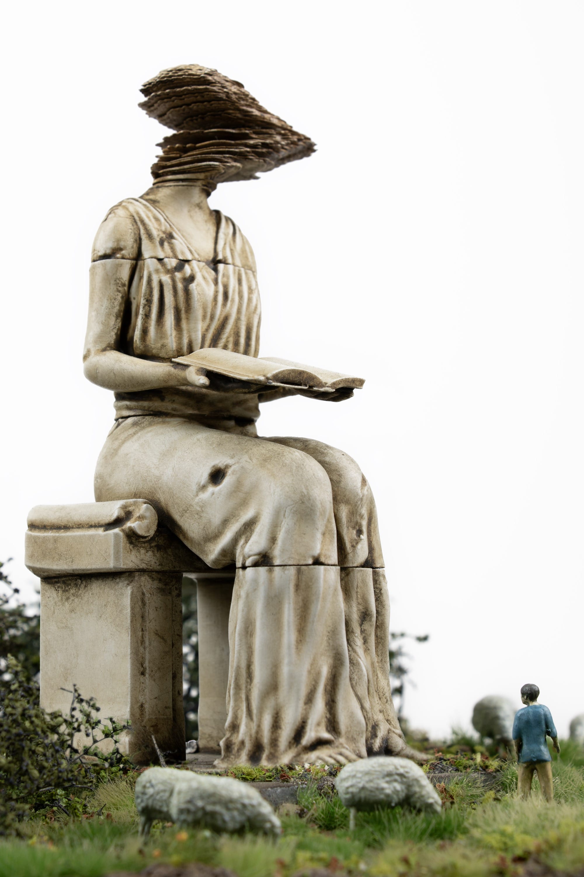 miniature figures look up at a seated statue with a glitch for a head