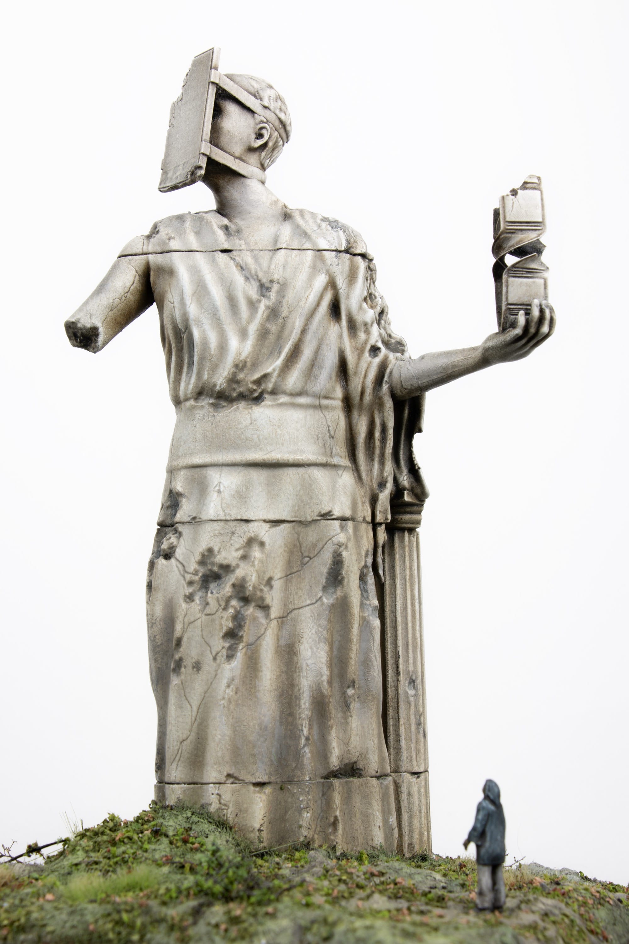 a miniature figure looks up at an antique statue with a device strapped to her face