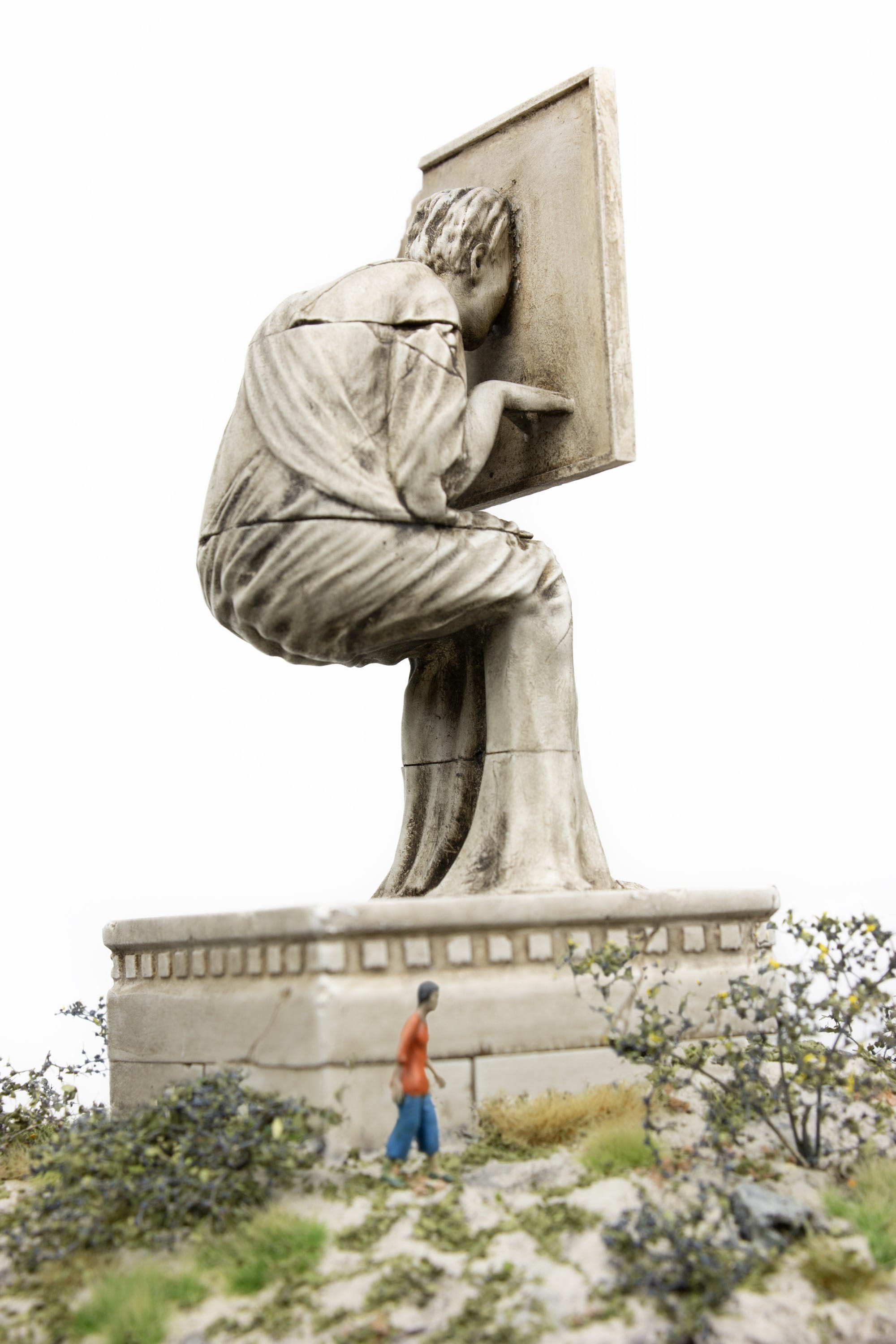 a small figure looks up at a statuesque figure hunched over with their face half inside a screen