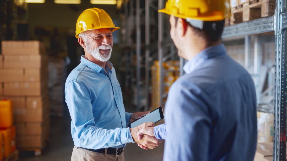 two men wearing yellow construction helmets shaking hands