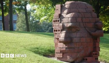 A brick-built statue depicting the head of Josiah Wedgwood in a stylised fashion. It is positioned on a grass verge.