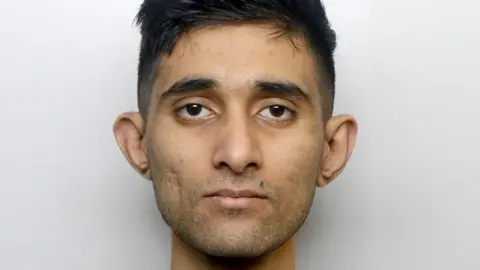 West Yorkshire Police A man with short dark hair staring at the camera.