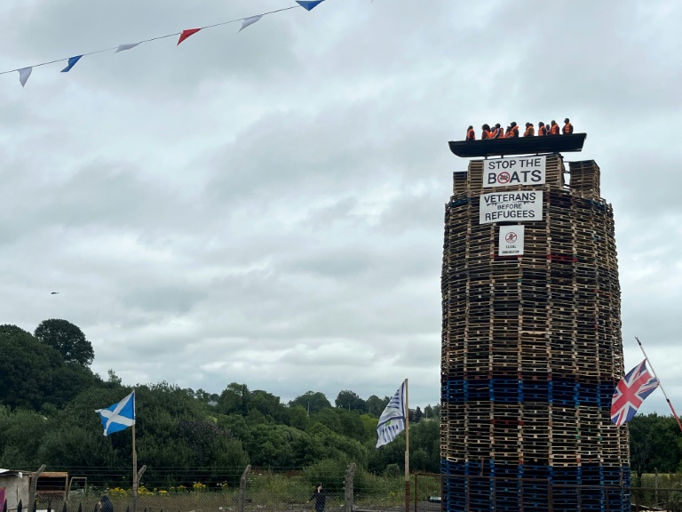 The migrant effigy had been hoisted atop a stories-tall stack of wooden pallets, one of hundreds of pyres lit each year in the run-up to July 12, a historically Protestant celebration (Peter MURPHY)