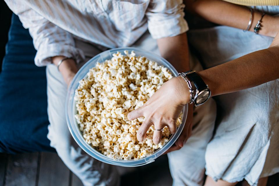 A from above view of an anonymous Asian woman and her Indian boyfriend eating snacks while spending their leisure time together.
