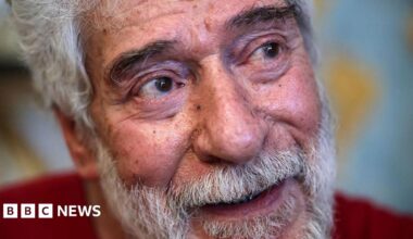 Georges Abdallah, a grey-haired 74-year-old with grey moustache and beard, sits in his prison cell in a red shirt