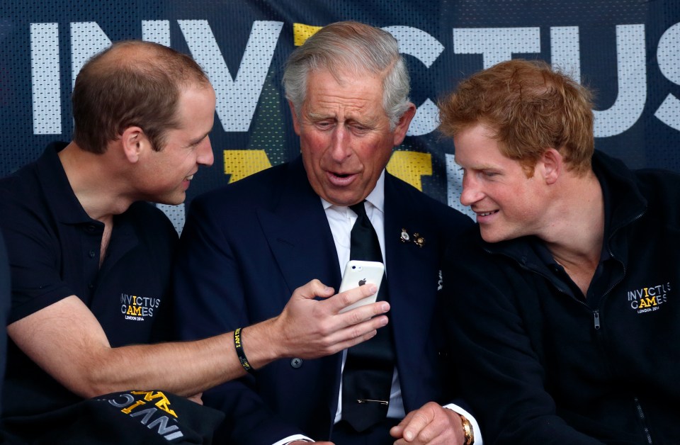 Prince William, Prince Charles, and Prince Harry looking at an iPhone.