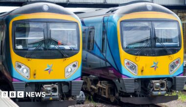 Two brightly coloured trains stand side by side on some tracks. The destination of both, indicated by a sign in their respective windows, is Sheffield.