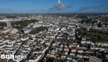 Ariel shot of South St Helier. Jersey. There are rows of houses and buildings below. The photo was taken on a cloudy day.