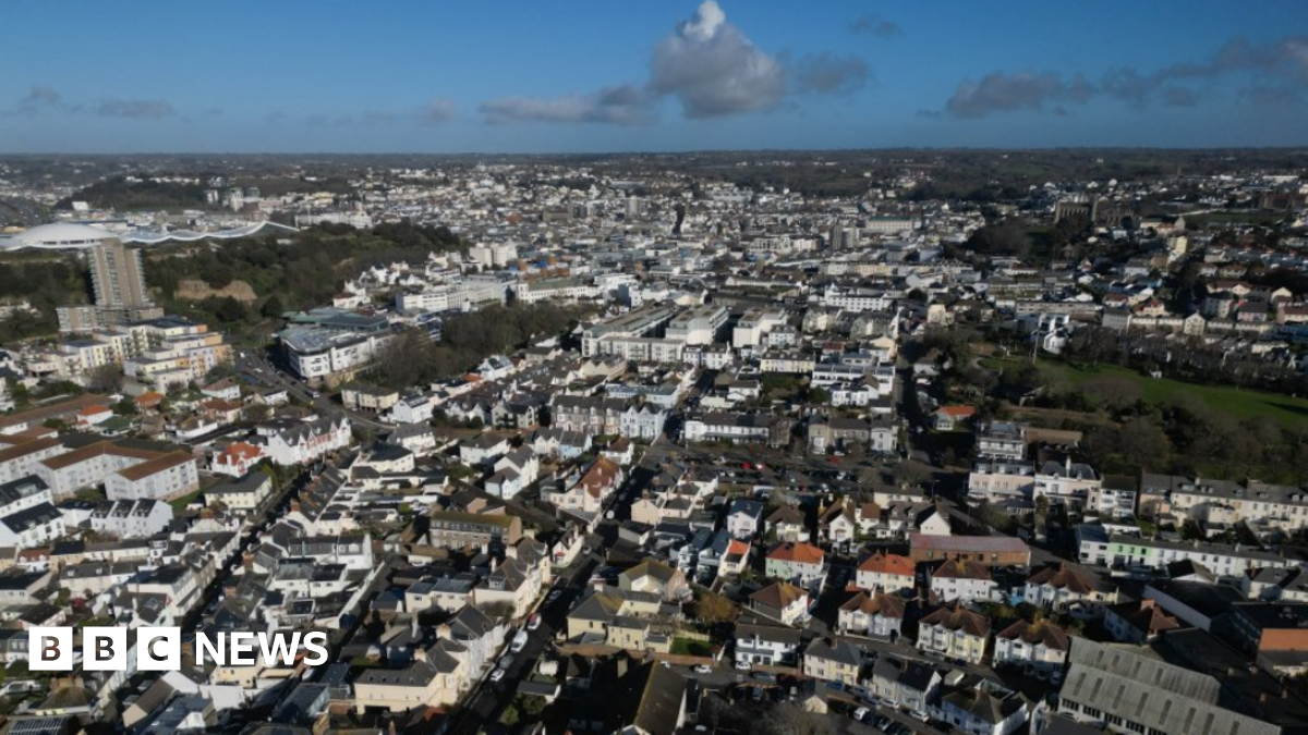 Ariel shot of South St Helier. Jersey. There are rows of houses and buildings below. The photo was taken on a cloudy day.