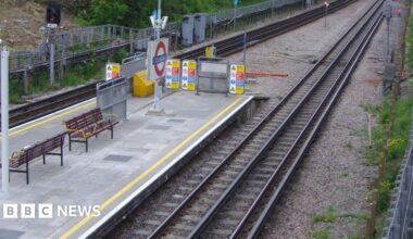 Colindale station platform as seen from above shows Tube roundel, wooden benches and train tracks