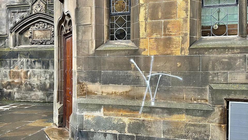There is a white graffiti tag on the wall of the cathedral.