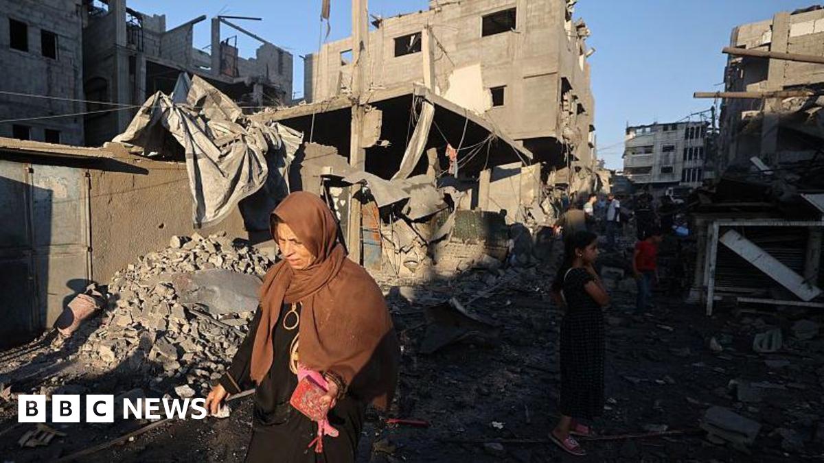 A Palestinian woman walks past damaged buildings after an Israeli strike on the Bureij refugee camp in the central Gaza Strip. Photo: 23 July 2025