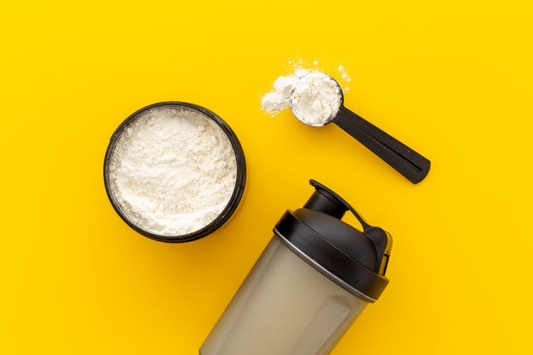 Jar and scoop filled with powder against yellow background.