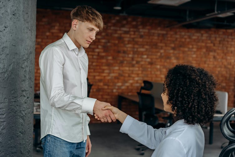 A woman shakes hand with a man at the beginning of a job interview.