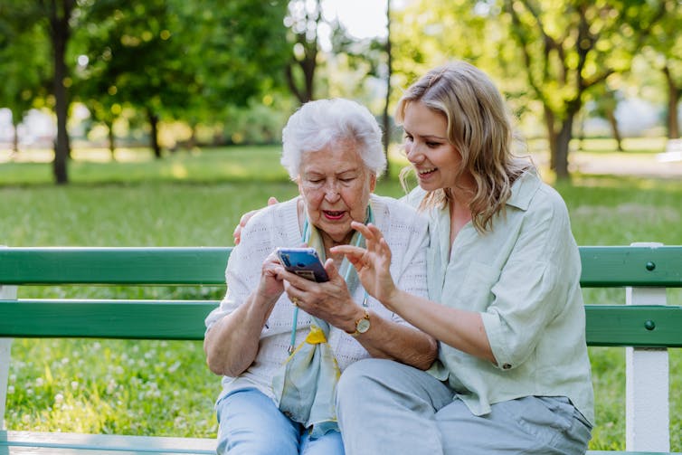 Two women of different generations use a smartphone together.