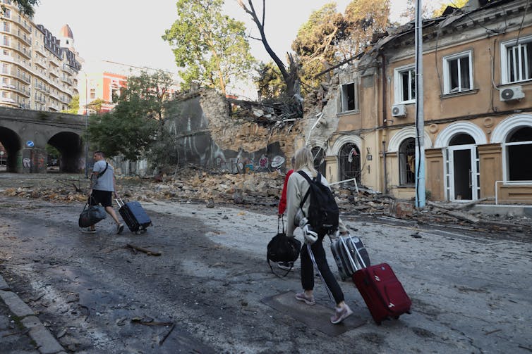 Local residents walk past buildings damaged as a result of a missile strike in Odesa.