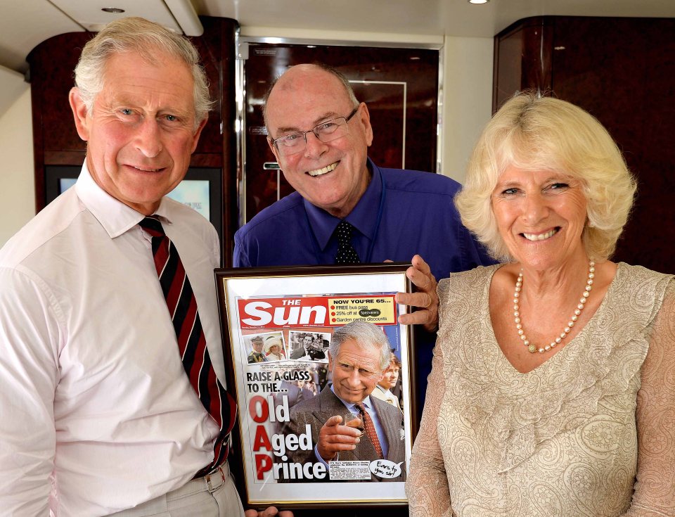Photograph of Prince Charles and Camilla, Duchess of Cornwall, on a flight, being presented with a framed copy of The Sun newspaper celebrating the Prince's 65th birthday.