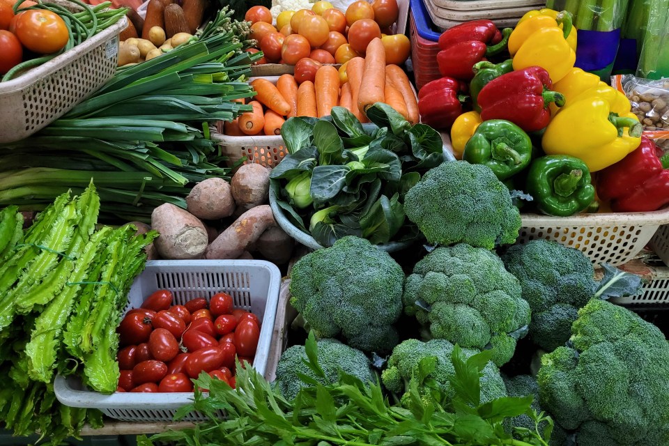 Fresh vegetables and fruits at an Asian market stall.
