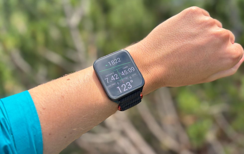 a person wearing a colourful square smartwatch while hiking