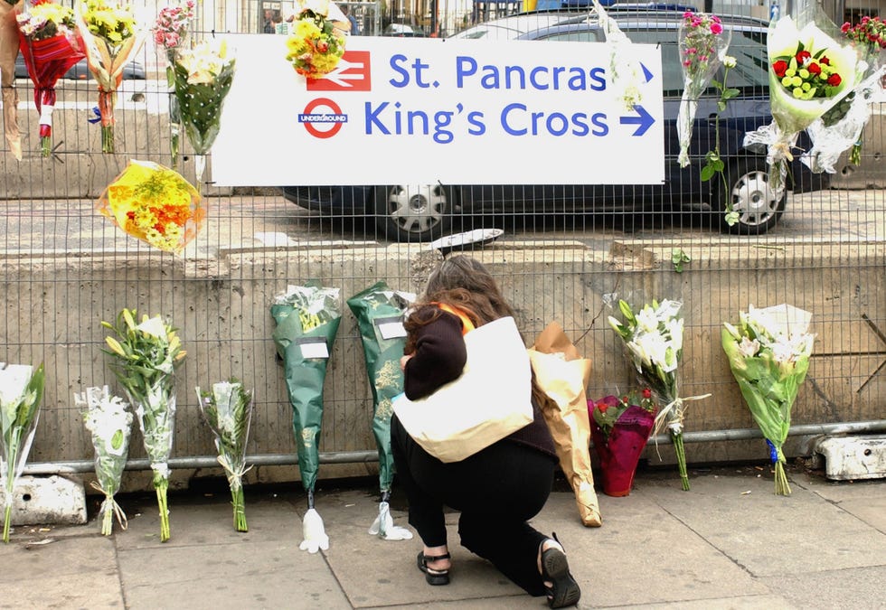 a pedestrian leaves a bouquet of flowers outside kings cross station 08 july 2005, following the 07 july bomb explosions in london, as the number of deaths appears to be larger than initially stated. british home secretary charles clarke admitted on friday that the london bomb attacks that killed more than 50 people came out of the blue and insisted that they did not represent a failure by intelligence services. afp photo/martyn hayhow (photo credit should read martyn hayhow/afp via getty images)