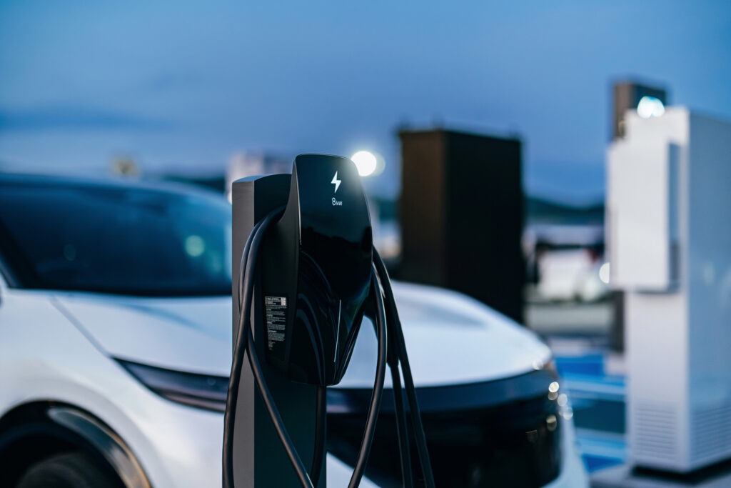 An electric vehicle at charging station in carpark in the city. A car is being charged. Designated parking space for eco-friendly hybrid cars.