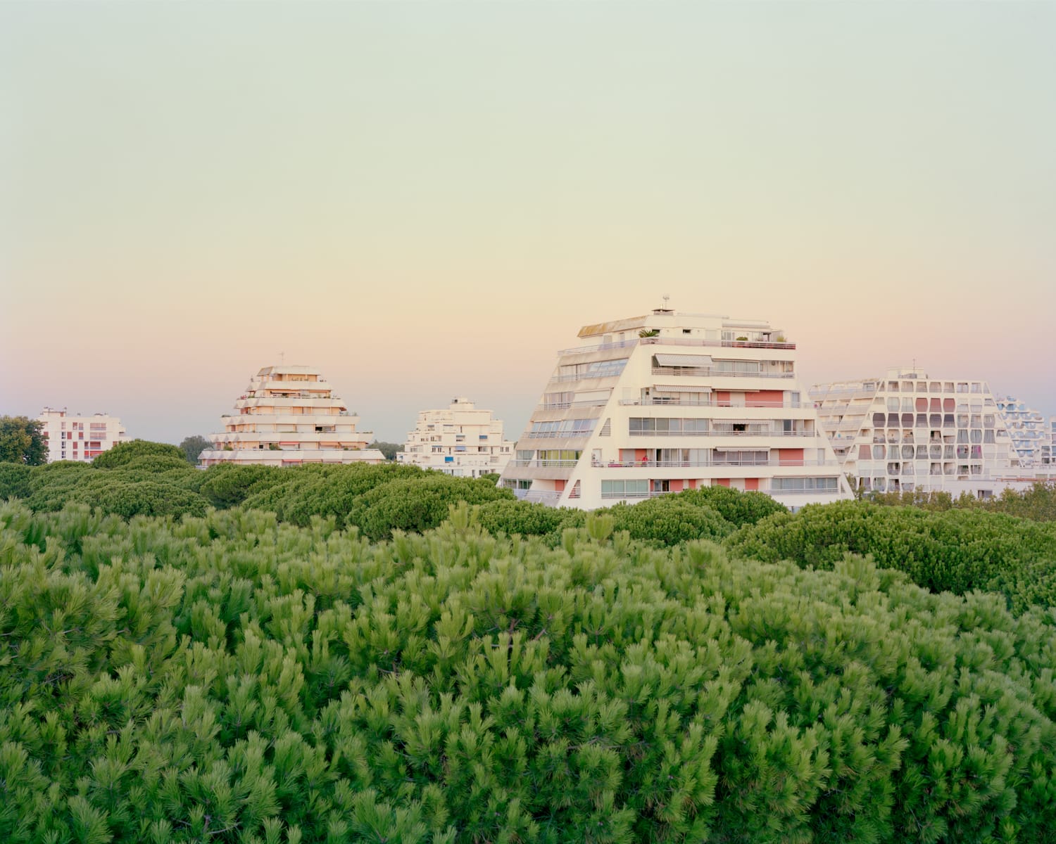 a modernist resort apartment complex in all-white against a sunset
