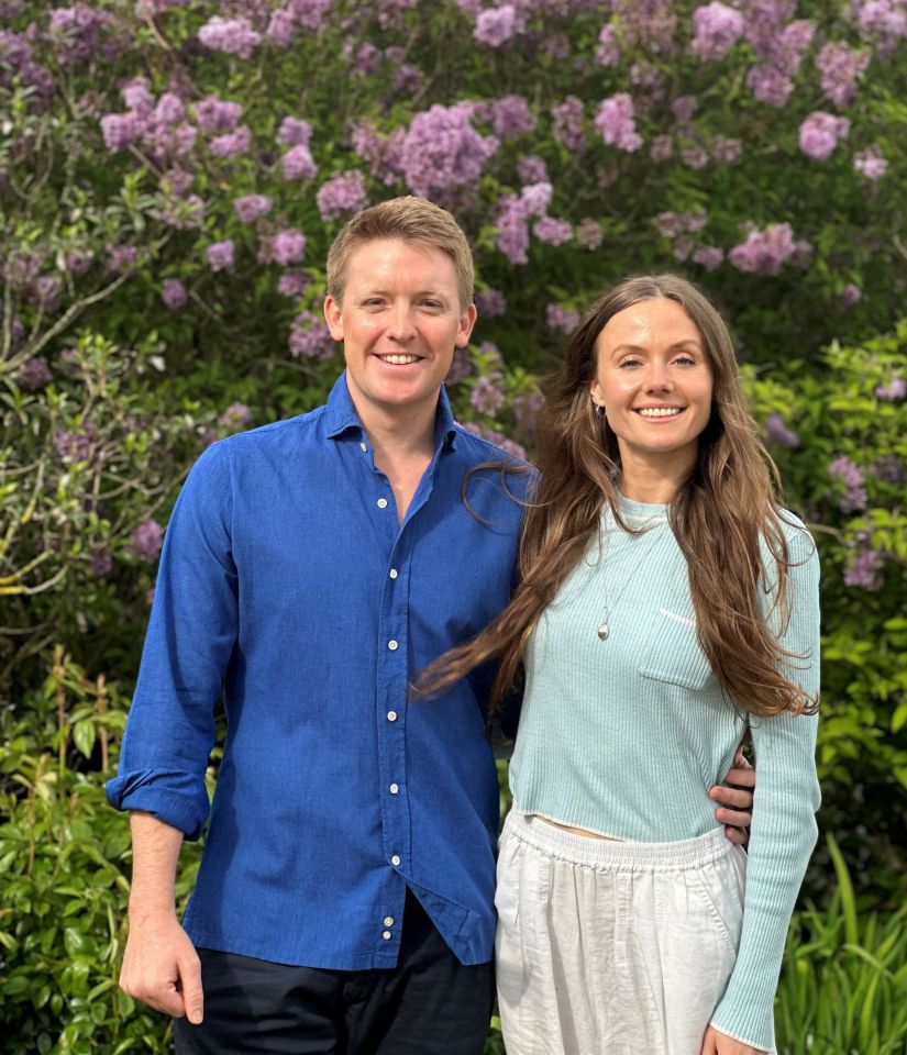Photo of Hugh Grosvenor and Olivia Henson in front of lilac bushes.
