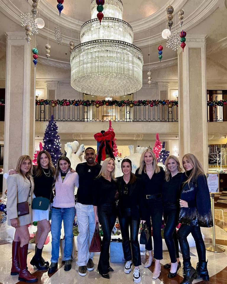 Group photo of women and one man in a hotel lobby decorated for Christmas.