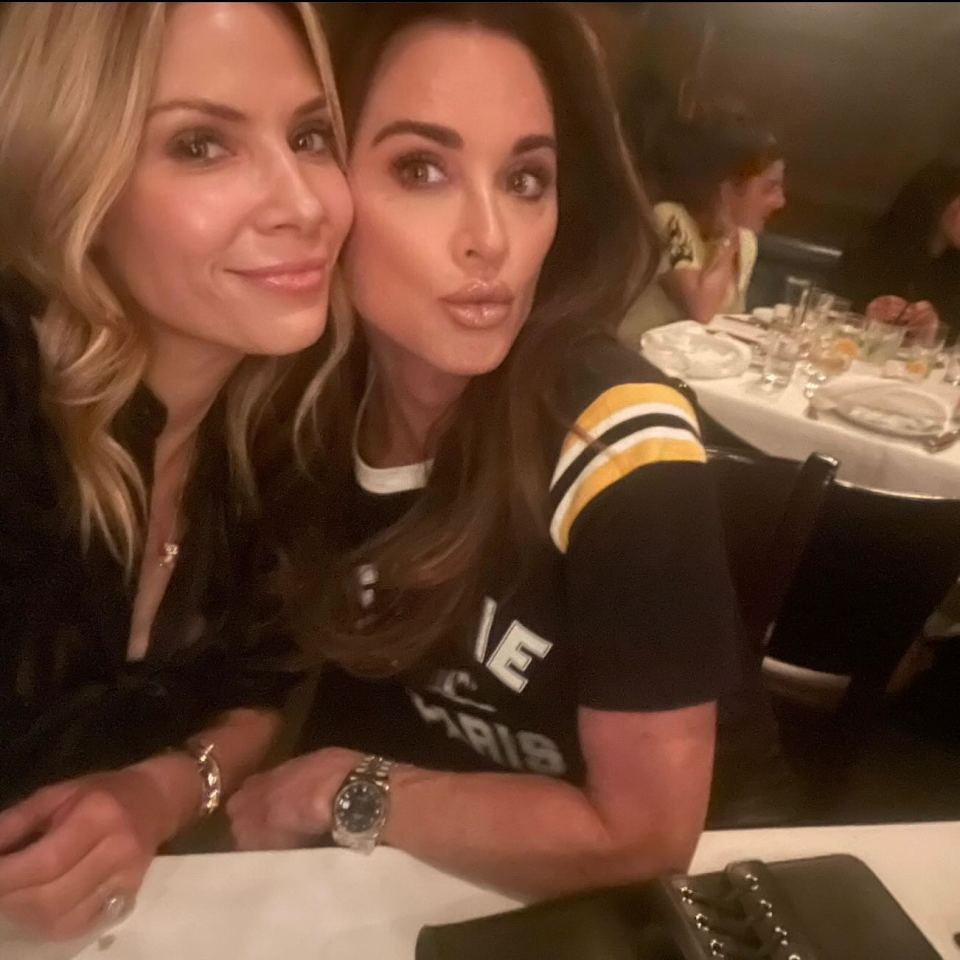 Two women sitting at a table, smiling for a selfie.