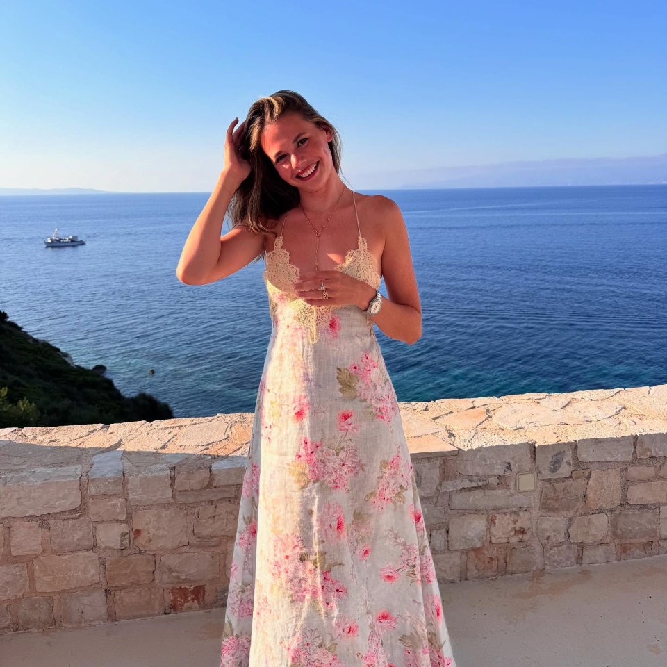 Woman in floral dress overlooking ocean.