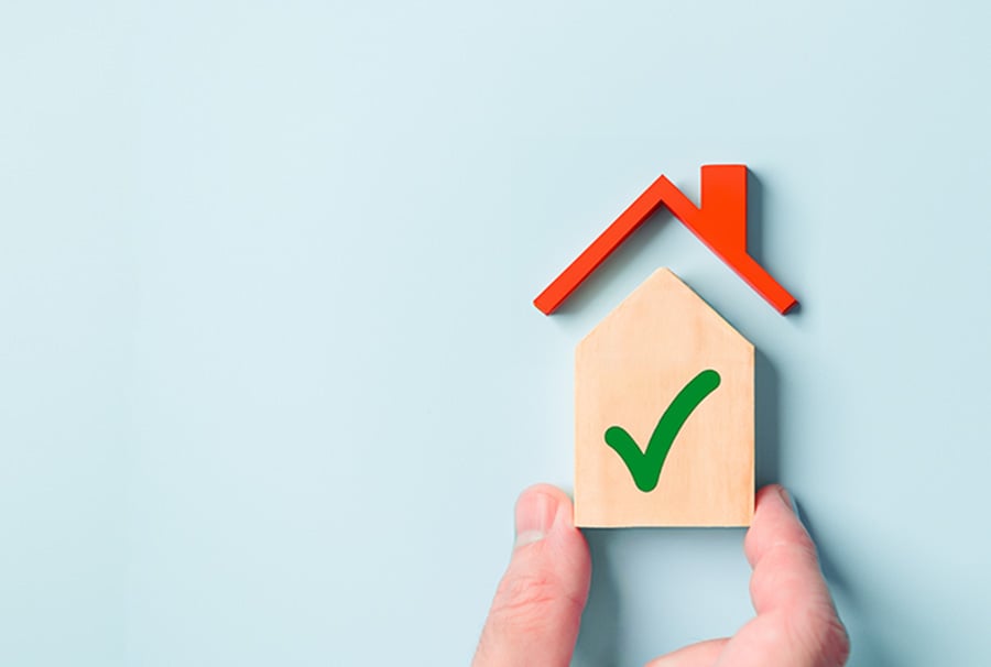 A basic house shape with a green tick painted on it set against a blue background