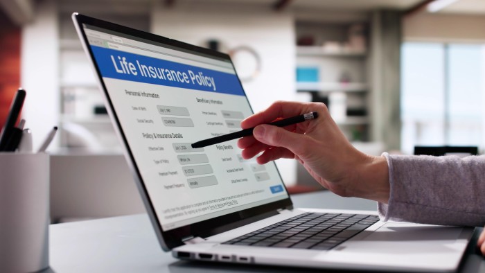 A person filling out a life insurance policy application form on a laptop
