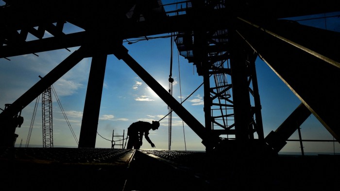 A worker is silhouetted at the construction site of the Olmeca oil refinery