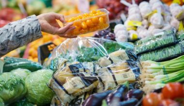 The hand of a shopper picking fruits and vegetables at an indoor market