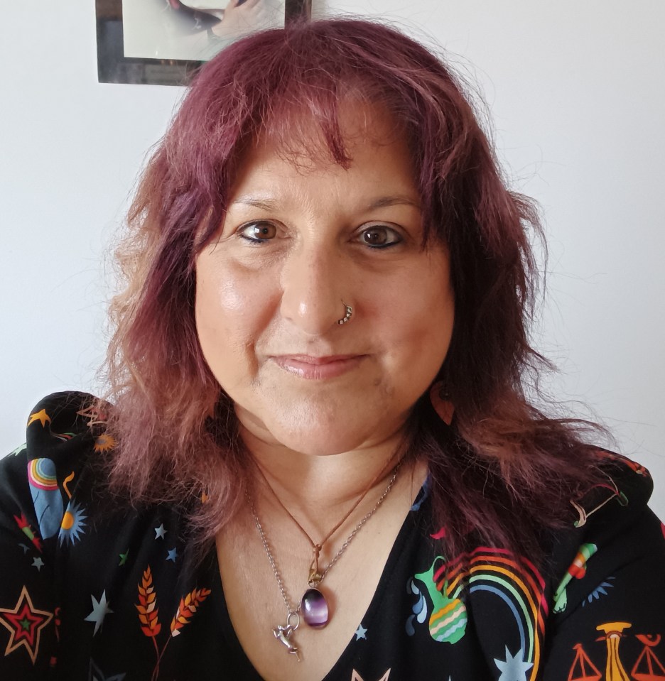 Portrait of Melanie Rushforth, a woman with burgundy hair, a nose piercing, and several necklaces.