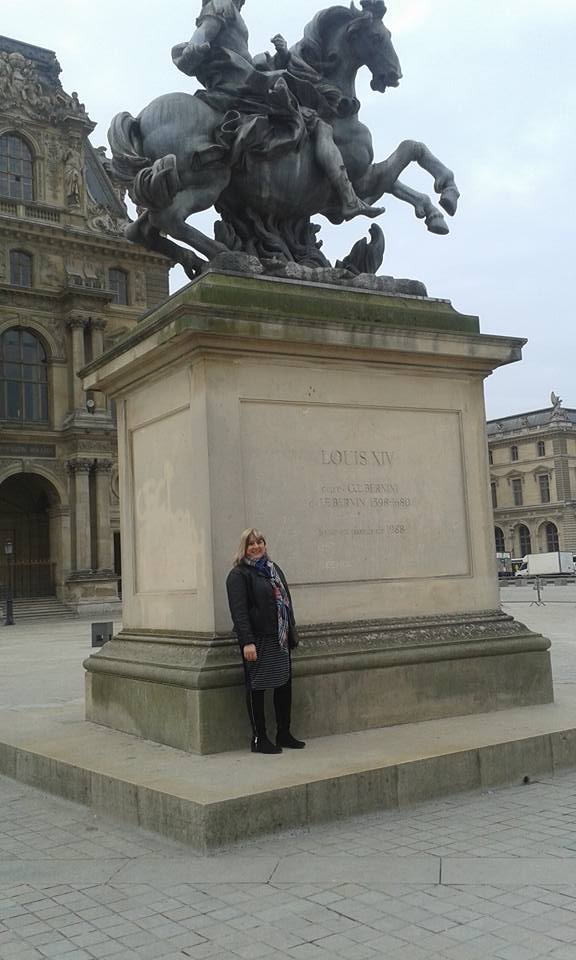 Person standing next to a statue of Louis XIV on horseback.