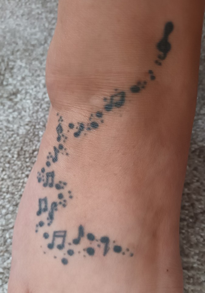 Tattoo of musical notes on a person's ankle.
