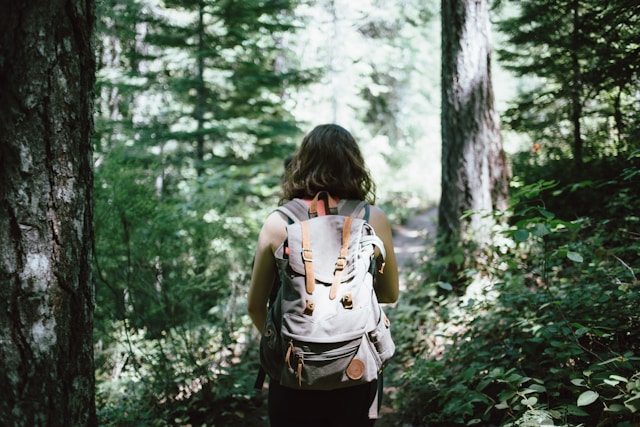 A woman hikes though a forested path.