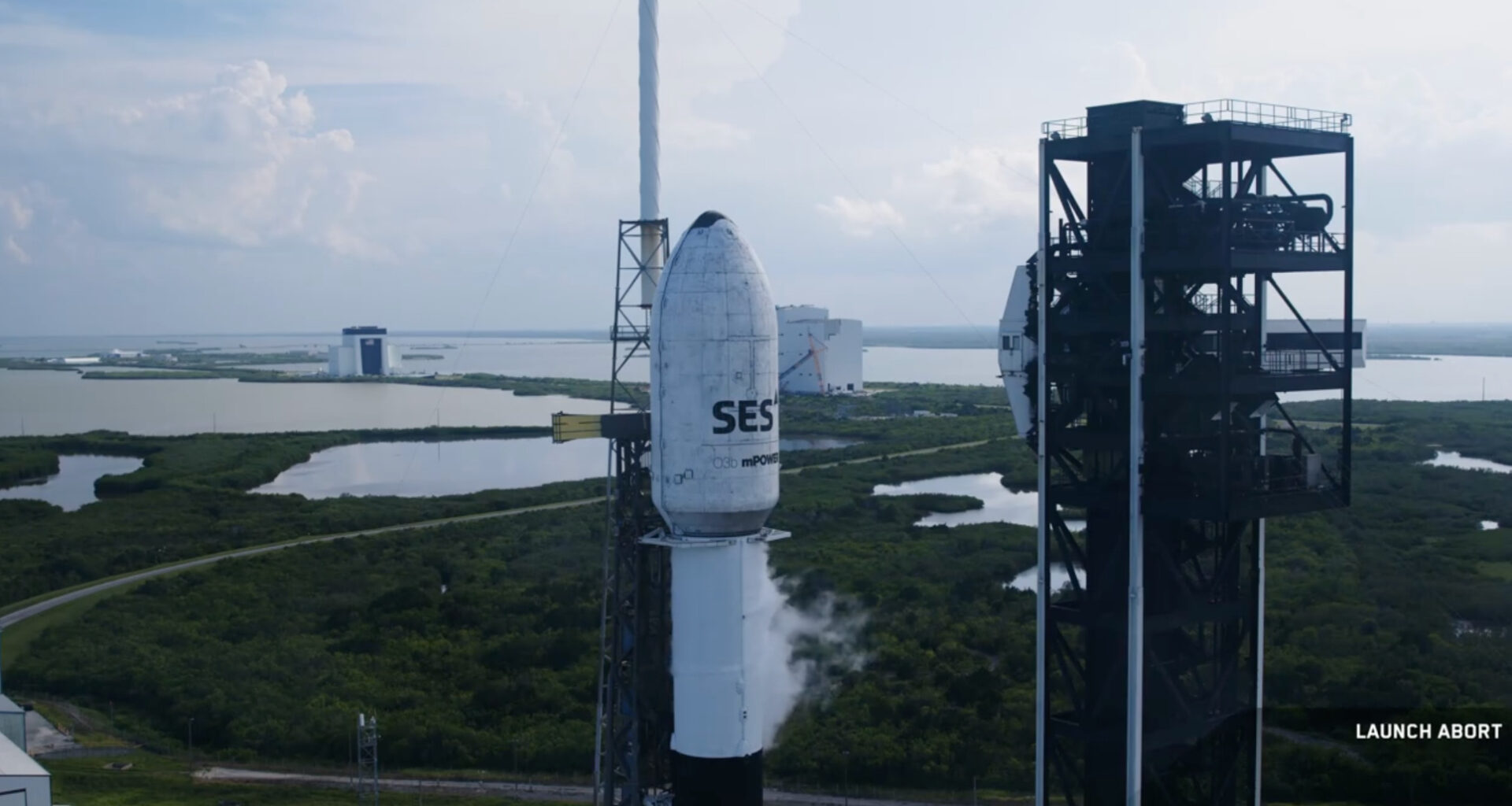 a white rocket stands on a seaside launch pad