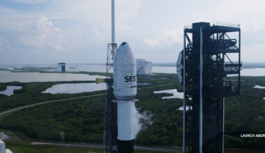 a white rocket stands on a seaside launch pad