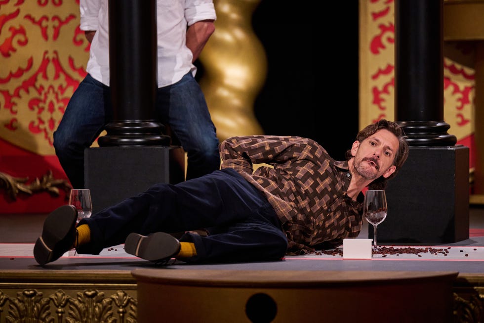 mathew baynton lying on the floor surrounded by spilled coffee beans and a glass on taskmaster