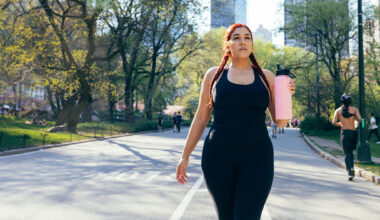 Woman walking in Central Park holding large pink water bottle