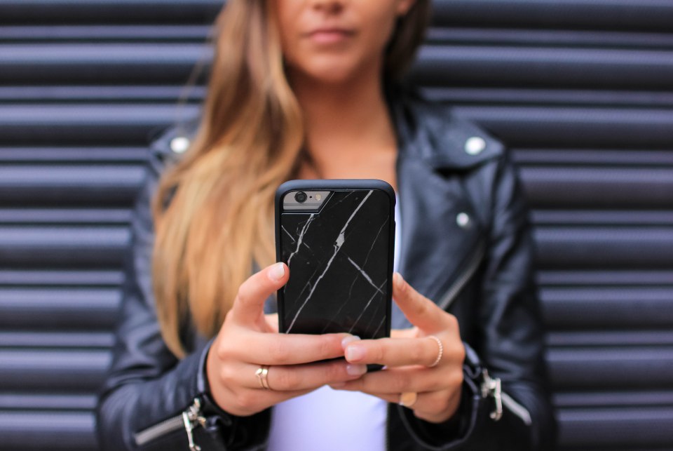Woman holding phone in black marble case.