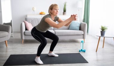Woman performing a shallow squat on a black exercise mat in a living room setting. there's a sofa behind her.