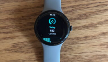 The Google Pixel Watch 3 sitting on a desk, showing a daily calorie count widget.